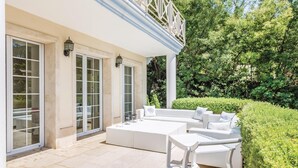 Un patio extérieur moderne avec un ensemble de canapés blancs, une petite table et une lanterne décorative.