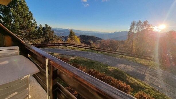 A scenic view from a balcony with a wooden railing, overlooking a road and distant mountains under a clear sky. - Cozy 4-person apt in Chaillol with balcony, near station (Saint-Michel-de-Chaillol)