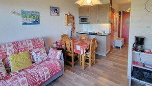 A cozy living room with a sofa, a dining table with chairs, a kitchen area with a microwave, and a coffee maker. - Cozy 4-person apt in Chaillol with balcony, near station (Saint-Michel-de-Chaillol)