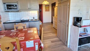 A compact kitchen with a microwave, a sink, and a dining area with a table and chairs. - Cozy 4-person apt in Chaillol with balcony, near station (Saint-Michel-de-Chaillol)