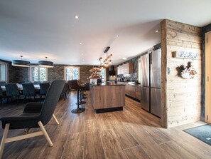 A modern kitchen with a central island, wooden flooring, and a stone accent wall.