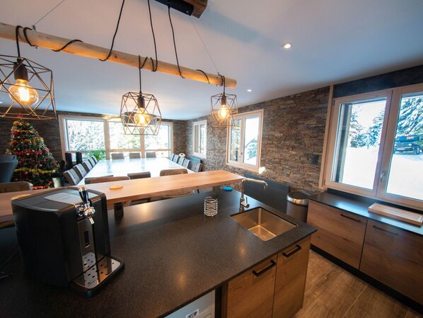 A modern kitchen with a large island, built-in appliances, and a stone accent wall.