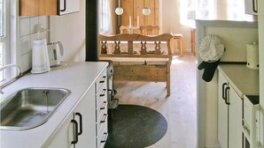 A kitchen with white cabinets, a sink, and a wooden dining table with chairs.