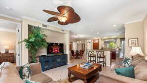 A living room with a television, sofa, coffee table, and a large plant.