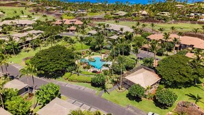 A resort with multiple buildings, a central pool, and a view of the ocean.