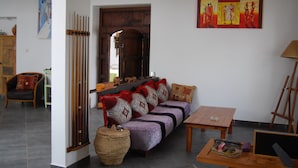 A living room with a sofa, a wooden table, a painting, and a wooden door. - Maison de Vacances a la Campagne Avec Piscine (ESSAOUIRA)