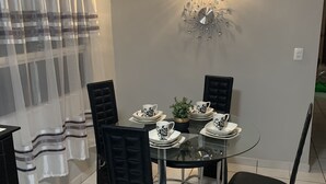 A dining area with a glass table, black chairs, and a decorative wall light. - Cozy 3 bedroom house in Ensenada Mexico (Ensenada)