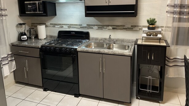 A modern kitchen with a gas stove, oven, microwave, and a double sink. - Cozy 3 bedroom house in Ensenada Mexico (Ensenada)
