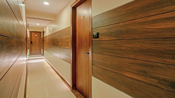 A corridor with wooden panel walls and a door with a number plate. - Treebo Trend Oxford (Mumbai)