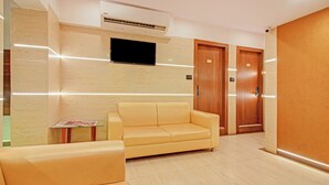 A hotel lobby with a yellow sofa, a small table with magazines, and two wooden doors labeled "501" and "502". - Treebo Trend Oxford (Mumbai)