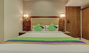 Ein Hotelzimmer mit einem Bett, zwei Nachttischlampen, einem Holzkopfstück, einem Nachttisch und einer Tür.