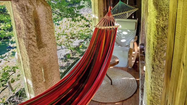 A hammock hanging between wooden beams in a rustic wooden structure with a view of a lush landscape. - FIFTH DO SOUTO (Barcia de Mera - COVELO)