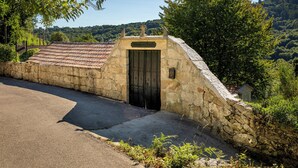 A stone building with a tiled roof and a wooden door, surrounded by greenery and hills. - FIFTH DO SOUTO (Barcia de Mera - COVELO)