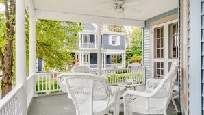A covered porch with white wicker chairs and a table, overlooking a two-story house with a balcony. - 12 Hurst - Chautauqua Charmer (Chautauqua)