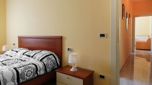 Een slaapkamer met een bed, nachtkastjes en een nachtkastje met een lamp.