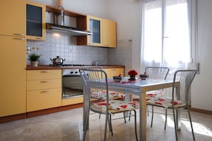 A kitchen with yellow cabinets, a stove, and a table with chairs.