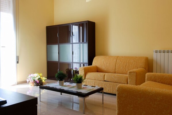 A living room with a sofa, a cabinet, and a coffee table with potted plants.