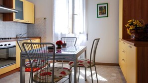 Een keuken met een eettafel, stoelen en een fornuis.