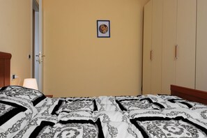A hotel room with a bed, a door, a wall-mounted picture, and a wardrobe.