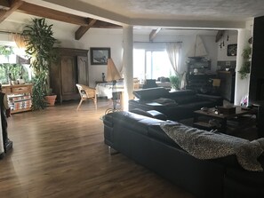 Relax in this inviting living area with a high ceiling, sofa, coffee table, and lush greenery.
