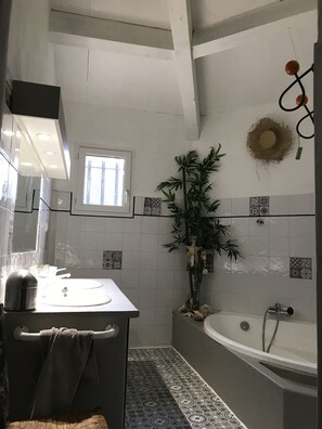 Bathroom features a sink, mirror, towel rack, and a bathtub with showerhead.