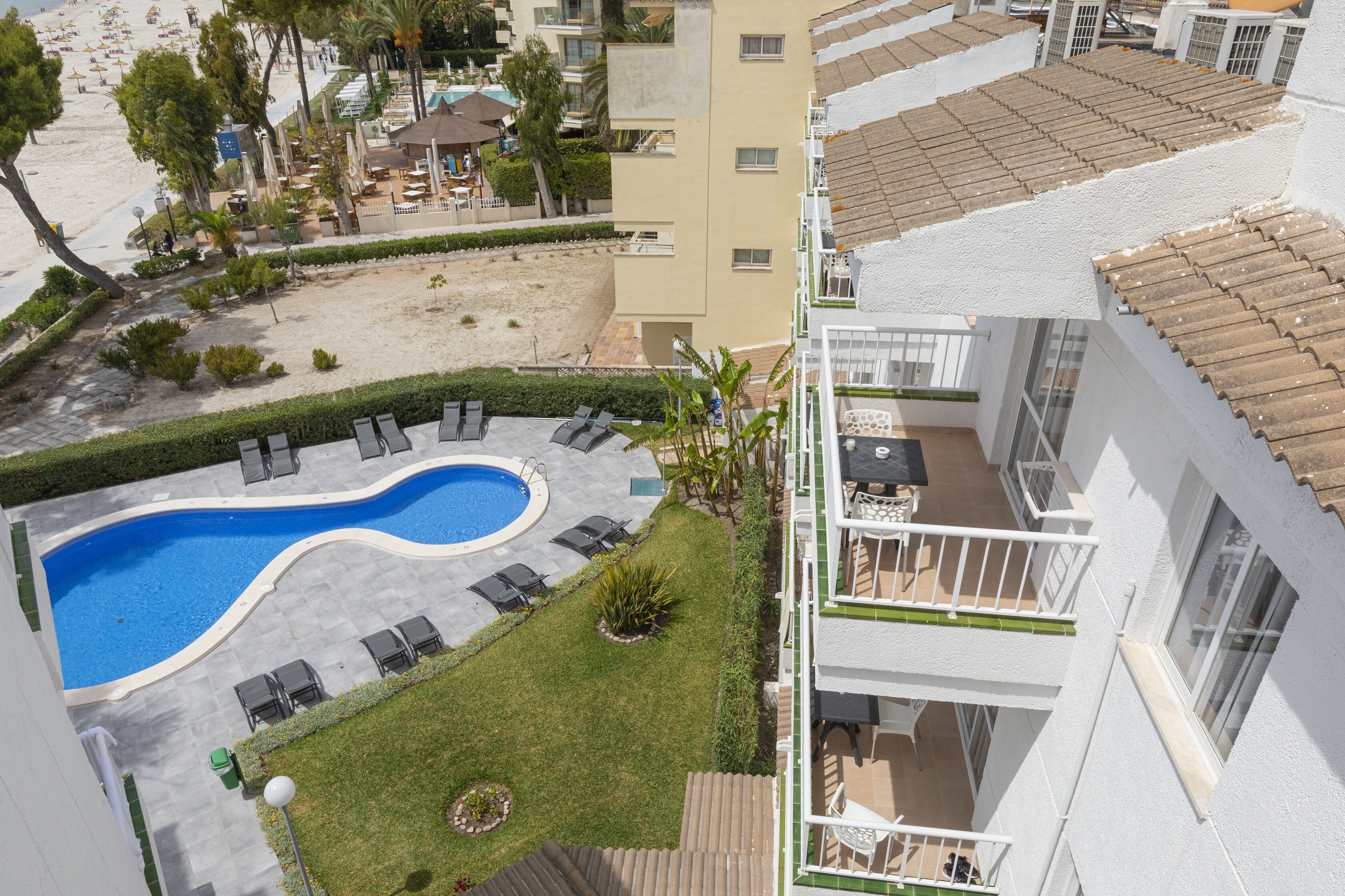 A rooftop pool area with lounge chairs, a swimming pool, and a view of the beach.