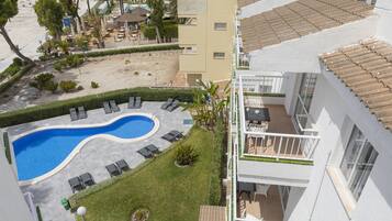 A rooftop pool area with lounge chairs, a swimming pool, and a view of the beach.