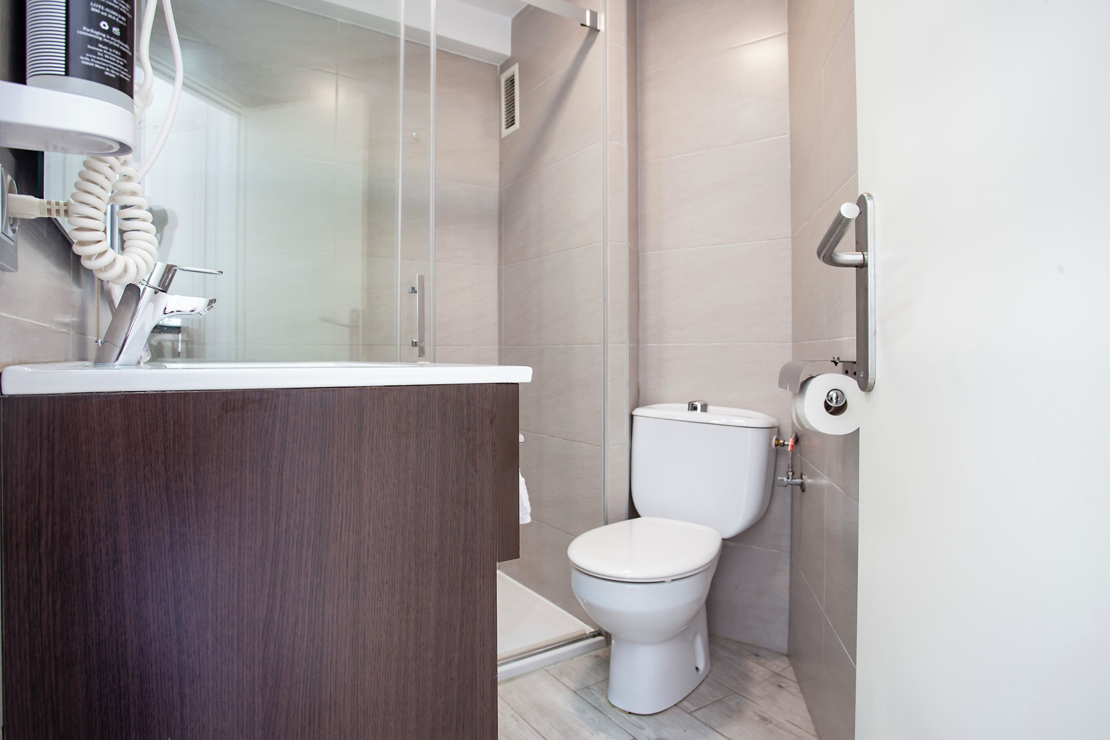 Un baño moderno con tocador de madera, inodoro y zona de ducha.