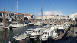 A marina with various boats docked, a waterfront promenade, and buildings with signage in the background. - 6 bedroom Traditional Farmhouse, large pool, indoor & outdoor games areas. (Rives-d'Autise)