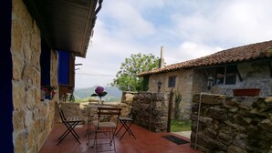 A patio with a table and chairs, a stone wall, and a view of the mountains.