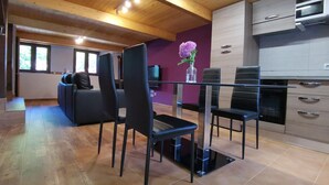 A modern kitchen with a dining area, wooden ceiling, and a purple accent wall.