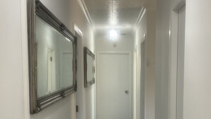 En smal hall med vita väggar, ett mattbeklätt golv och en dörr längst ner.