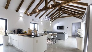 Une cuisine spacieuse avec un grand îlot central, des poutres en bois au plafond et un lustre.