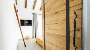 Une porte en bois avec une poignée en métal noir, dans une pièce qui contient un lit et une petite table.
