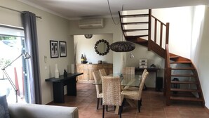 Un salon avec un canapé, une table à manger avec des chaises, un escalier et un coin cuisine.