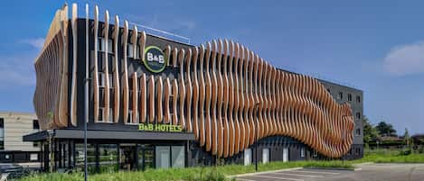 A modern hotel with a unique wooden facade and a clear sign reading "B&B HOTELS".