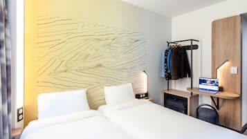 Una habitación de hotel moderna con una cama grande, un escritorio con una computadora portátil, un perchero y un diseño de pared único.
