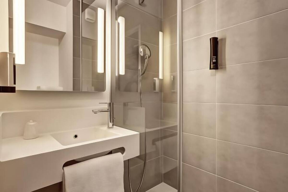 Ein modernes Badezimmer mit Waschbecken, Spiegel und Dusche.