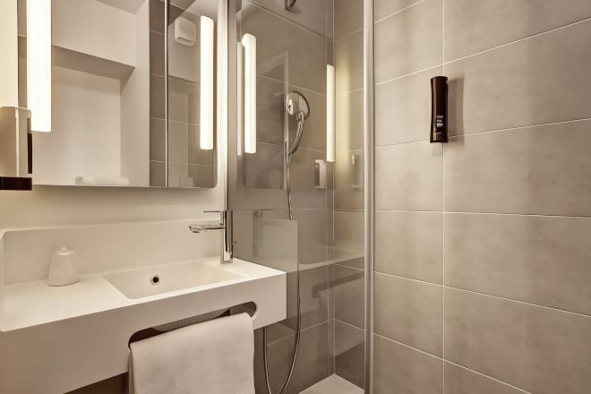 Un baño moderno con lavabo, espejo y ducha.
