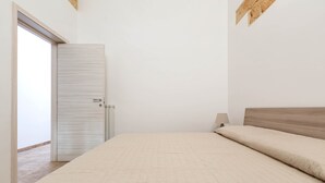 Una camera da letto con un letto, una testiera in legno, una porta e un comodino con una lampada.