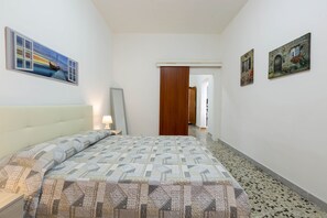 Een hotelkamer met een bed, nachtkastje, spiegel en twee schilderijen aan de muur.