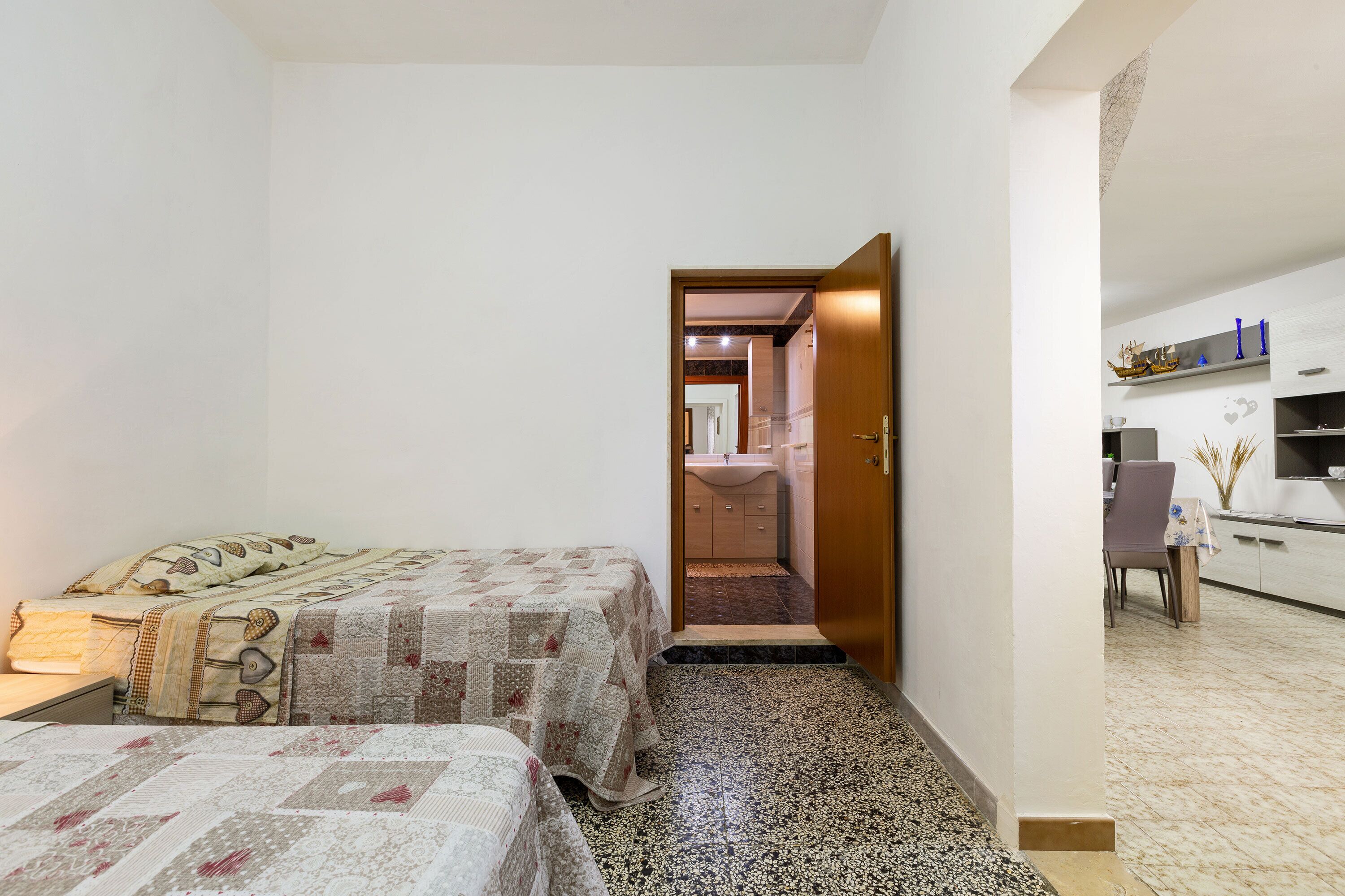 A bedroom with two beds, a bathroom, and a kitchenette.