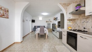 Cozinha moderna com área de jantar, incluindo fogão, forno e mesa com cadeiras.