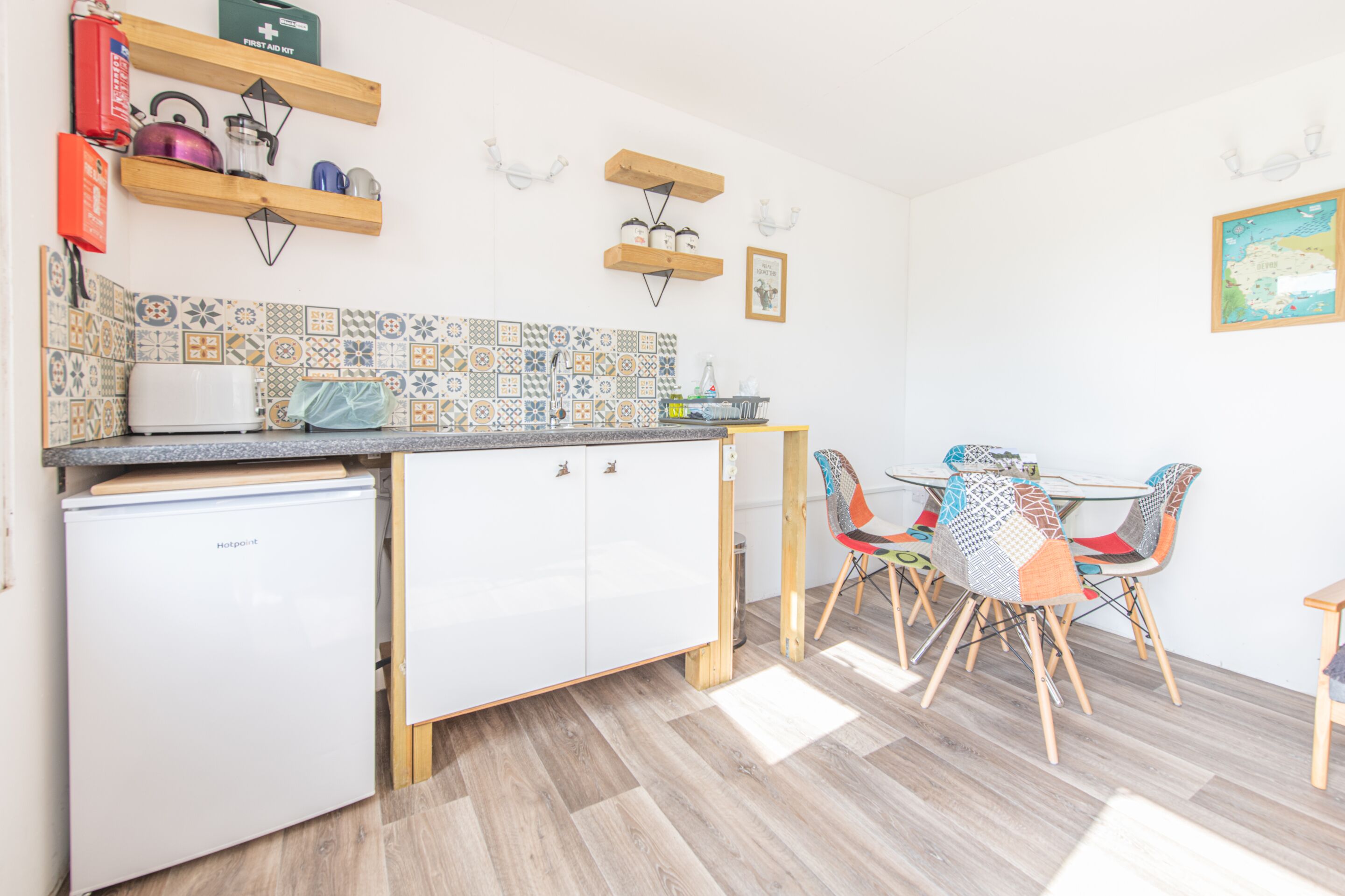 A compact kitchen with a refrigerator, a sink, and a dining area with a table and chairs.