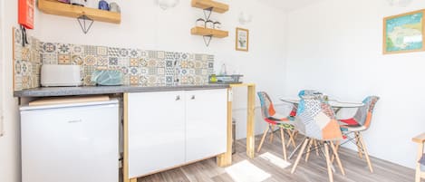 A compact kitchen with a refrigerator, a sink, and a dining area with a table and chairs.