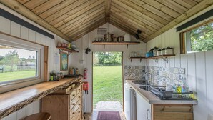 Cocina compacta con mostradores de madera, un lavamanos y una ventana con vistas a un jardín.
