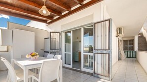 A spacious patio with a dining table and chairs, a sliding glass door leading to a kitchen, and a wooden ceiling. - 1868 A Casa di Luciano (Uggiano la Chiesa)