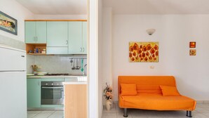 A compact living space with a kitchenette, a sofa, and a painting on the wall. - 1868 A Casa di Luciano (Uggiano la Chiesa)