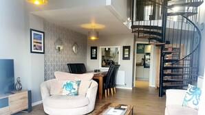 Ein modernes Wohnzimmer mit Sofa, Couchtisch und einer Wendeltreppe.