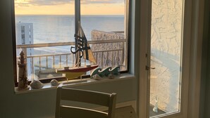 A room with a large window overlooking a coastal view, a small table, and a door with frosted glass. - Beautiful Ocean view corner unit (Myrtle Beach)